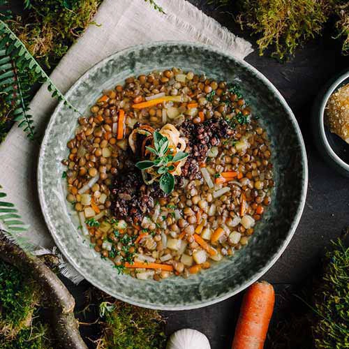 Der Linsenteller vom O´Gretel Restaurant ist von oben fotografiert und steht auf einem Waldboden.