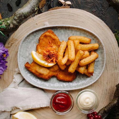 Das Kindergericht "Kleine Schnitzeljagt mit Klosspommes" auf einem Teller angerichtet. Daneben stehen zwei Schalen mit Mayo und Ketchup.