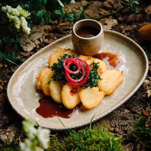 Ein gebratener Kloß mit Bratensauce. Serviert auf einem schönen beigen Teller auf einem Waldboden.