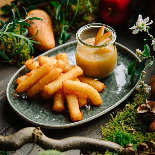 Kloßpommes mit Apfelmus sind eine kreative und leckere Kombination – angerichtet auf einem Teller, das Apfelmus in einem Glas.