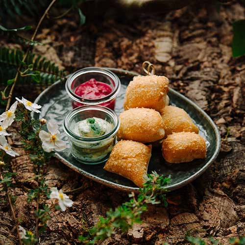 Gretels Kruemchen werden mit Preiselbeeren und Kräuteraioli serviert - angerichtet auf einem Waldboden.