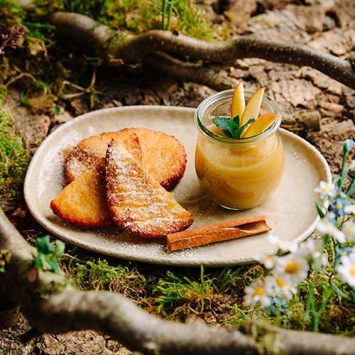 Das Dessert "Suesse Apfel Baeckchen": Die luftigen Quarkkeulchen harmonieren perfekt mit dem fruchtigen Apfelmus und bieten eine köstliche Mischung aus süß und saftig.
