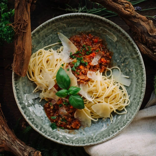 Ein Teller Nudeln Bolognese - von oben fotografiert. Steht auf einem Waldboden.