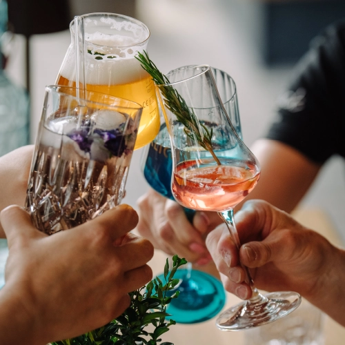 Mit vier unterschiedlichen Gläsern – Bier, Cocktail, Aperitif und Likör – stoßen sie an.